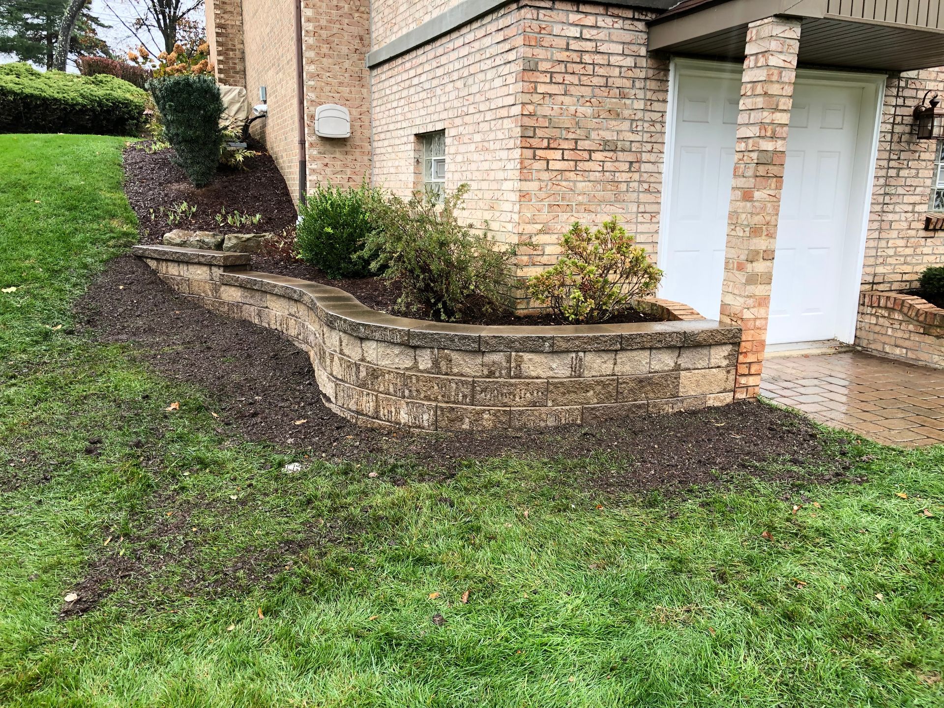 A brick wall with a planter in front of a house.