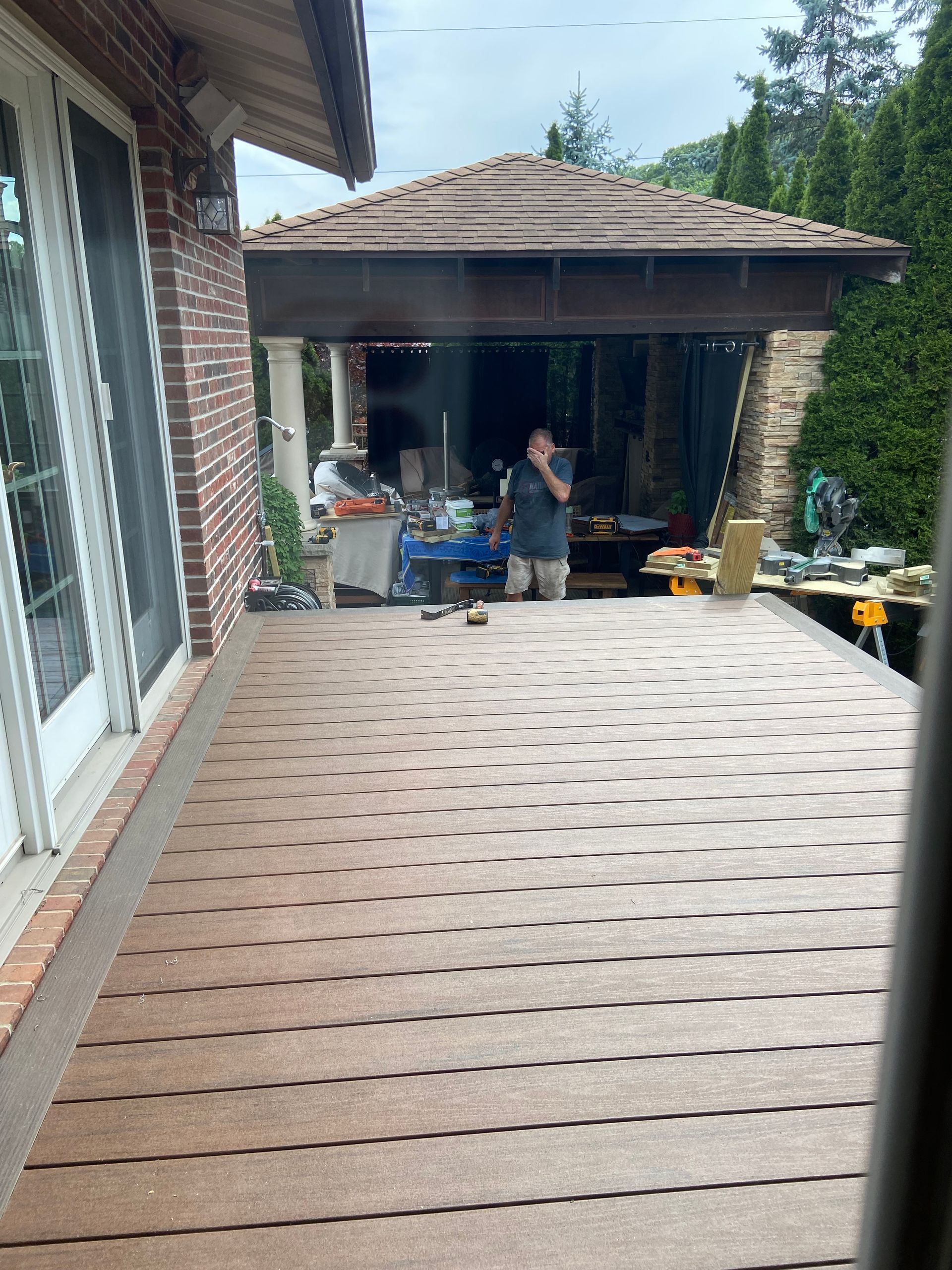 A man is standing on a deck under a gazebo.