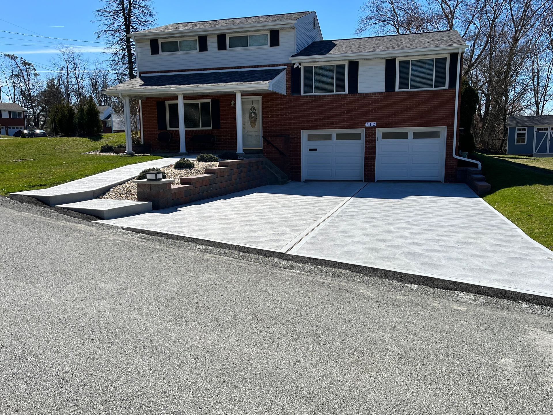 A brick house with a concrete driveway in front of it