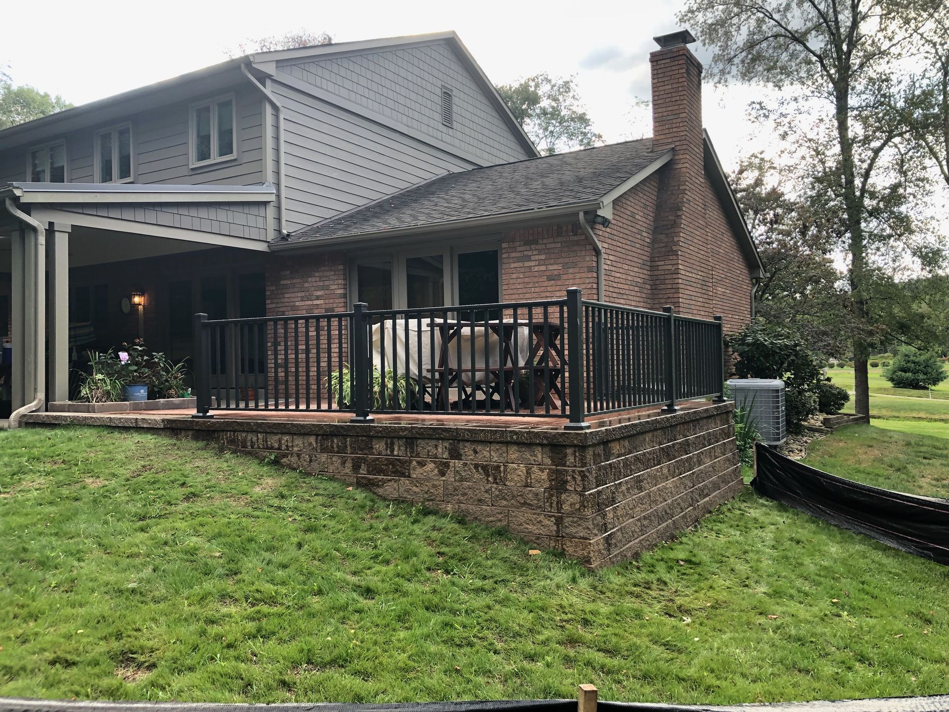 A large brick house with a large deck and a fence around it.