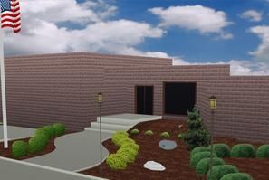 A brick building entrance with stairs, a walkway, landscaped bushes, rocks, two lampposts, and an American flag.