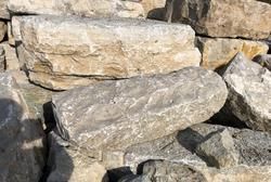Stacked natural limestone boulders with rough textures and varying shades of beige, tan, and grey.