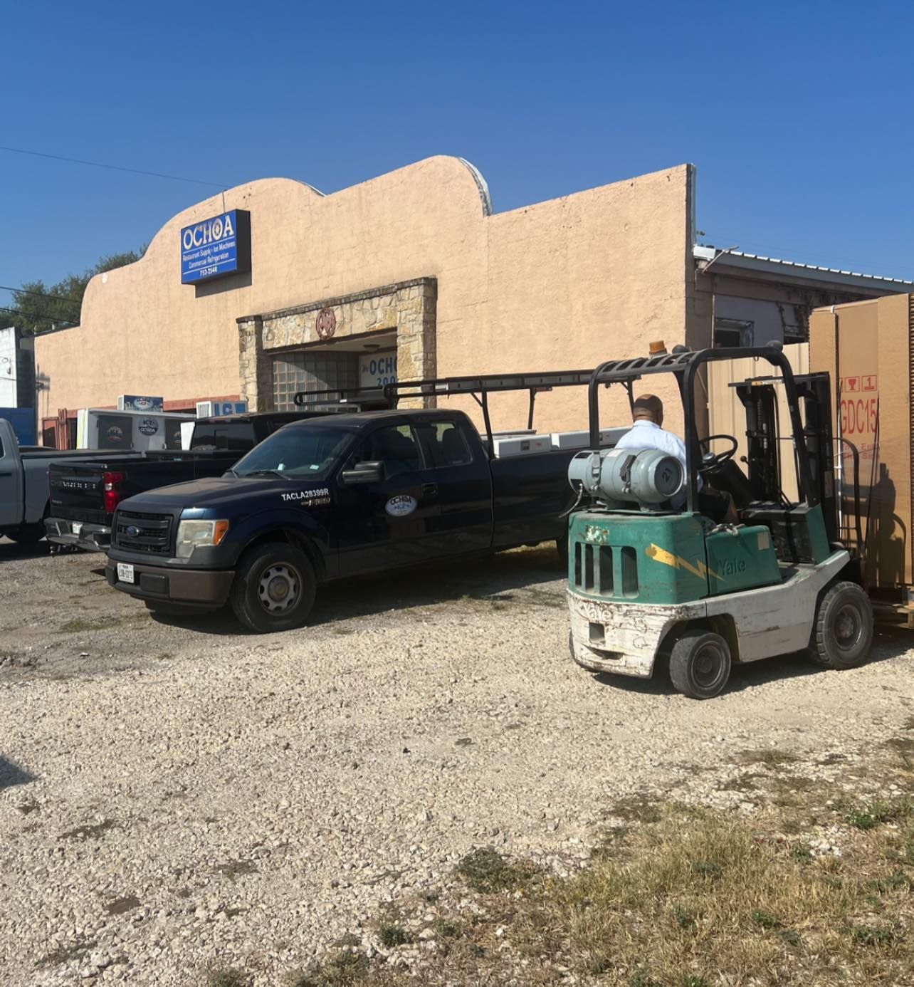 A truck and a forklift are parked in front of a building
