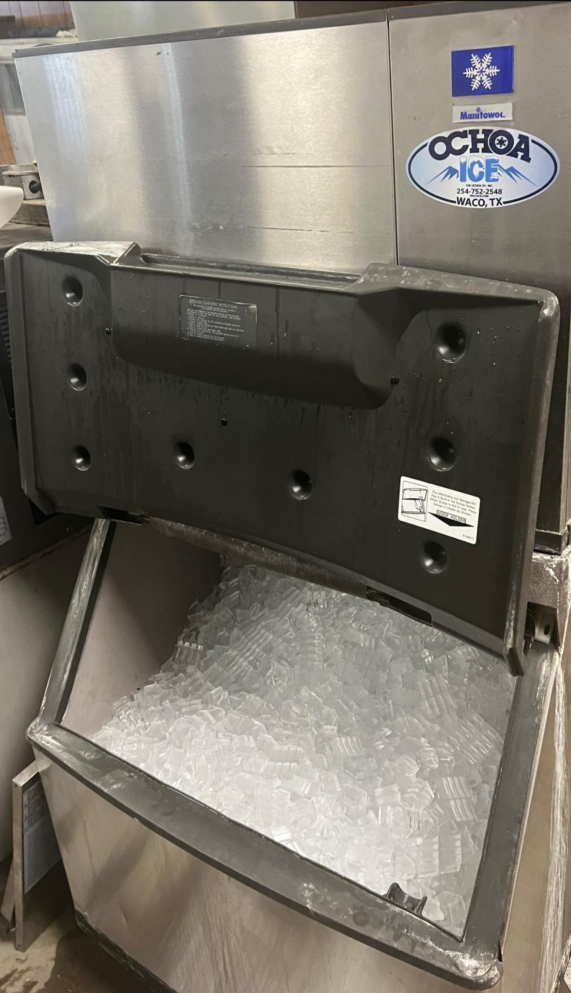 A stainless steel ice maker is sitting on top of a table.