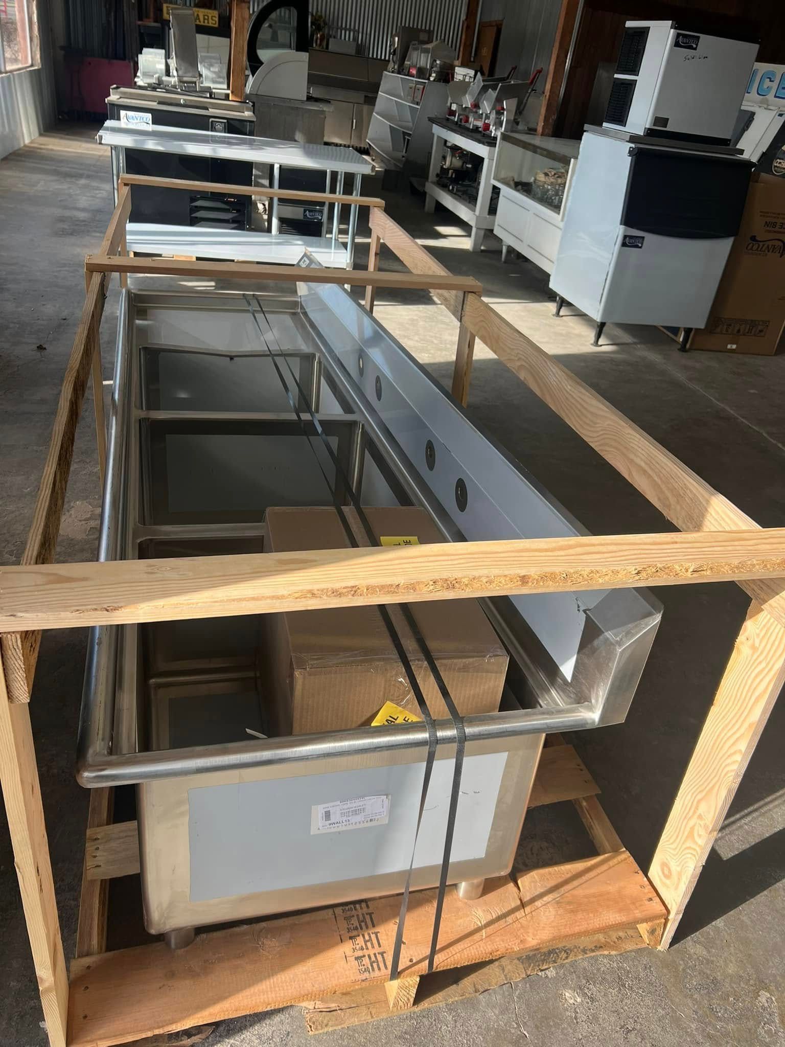 A stainless steel sink is sitting in a wooden crate.