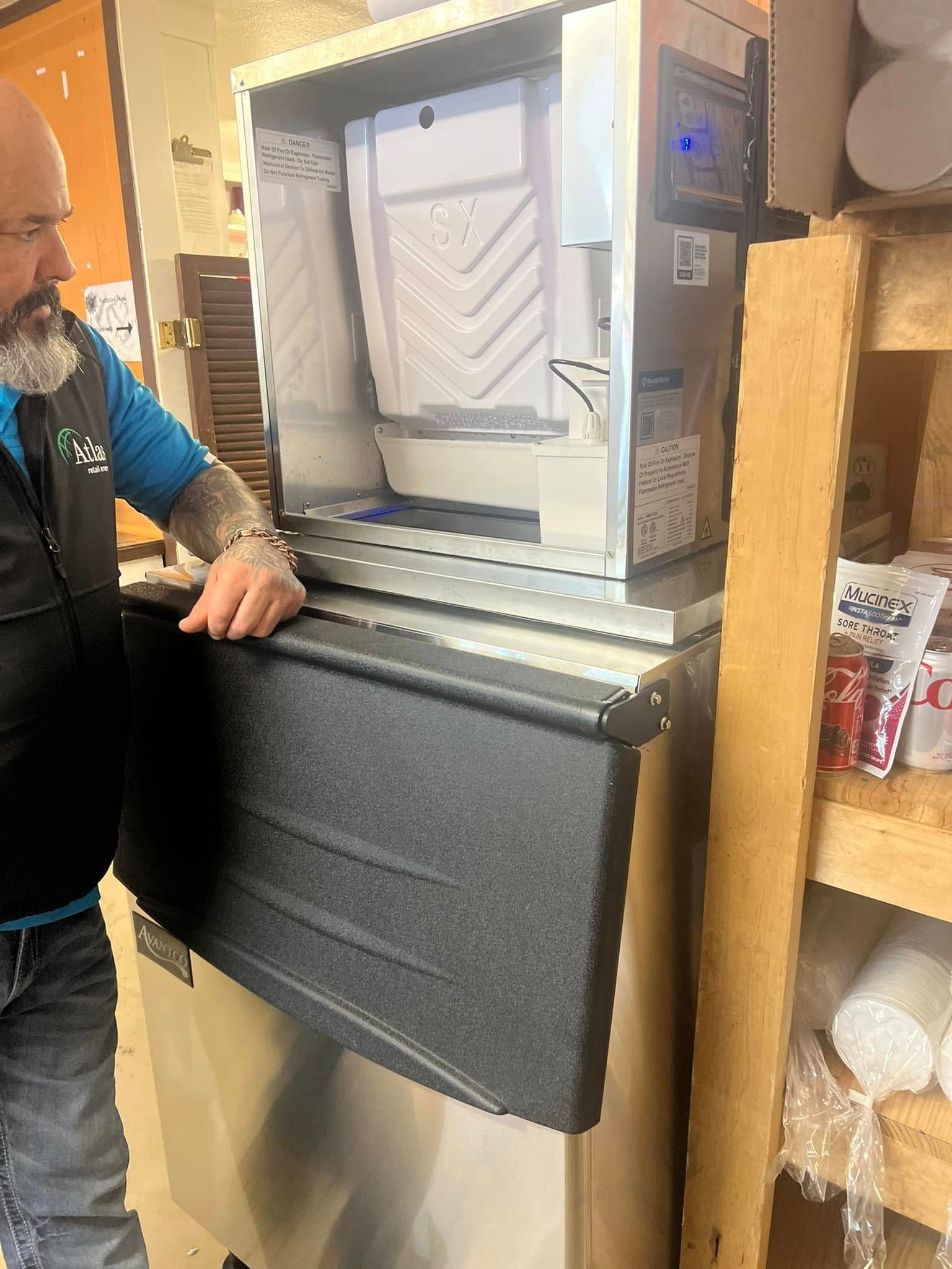 A man is standing next to an ice machine in a store.