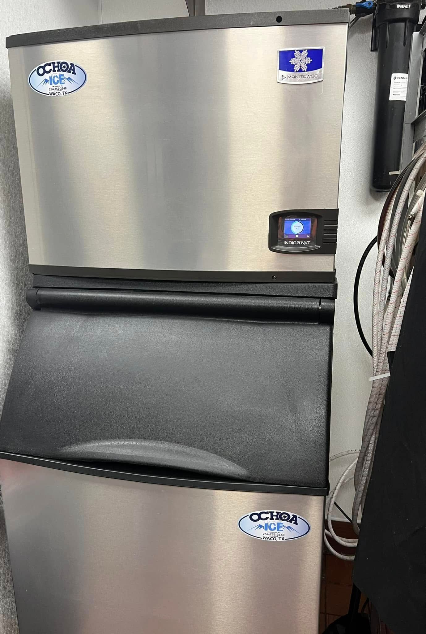 A stainless steel ice machine is sitting next to a black ice cube maker.