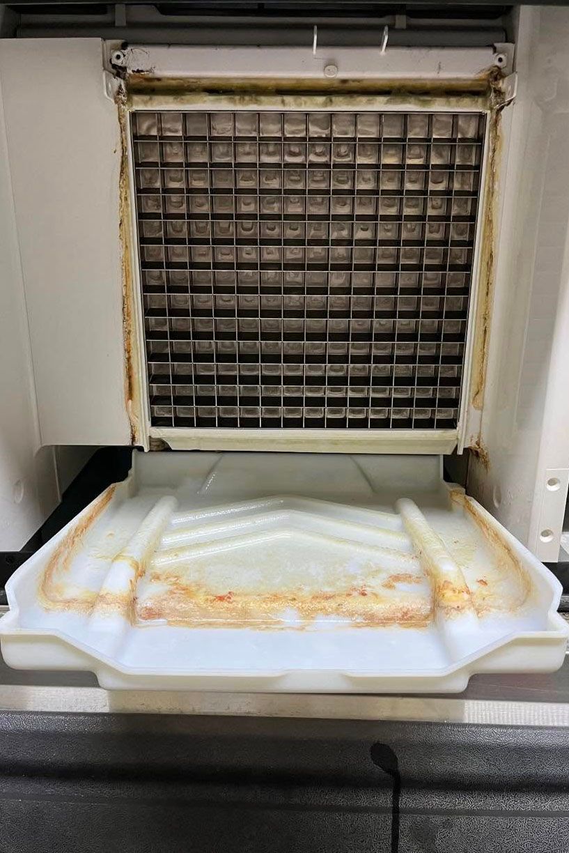 A dirty ice cube maker is sitting on top of a counter.