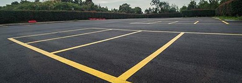 A parking lot with yellow lines on it and trees in the background.