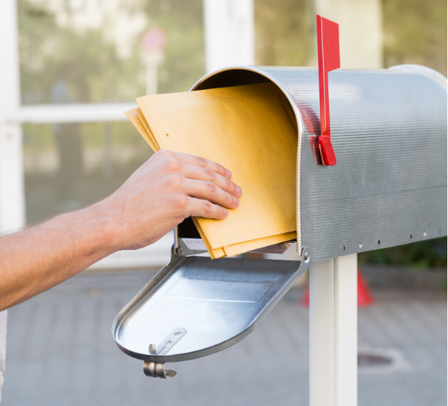 A person is putting an envelope into a mailbox