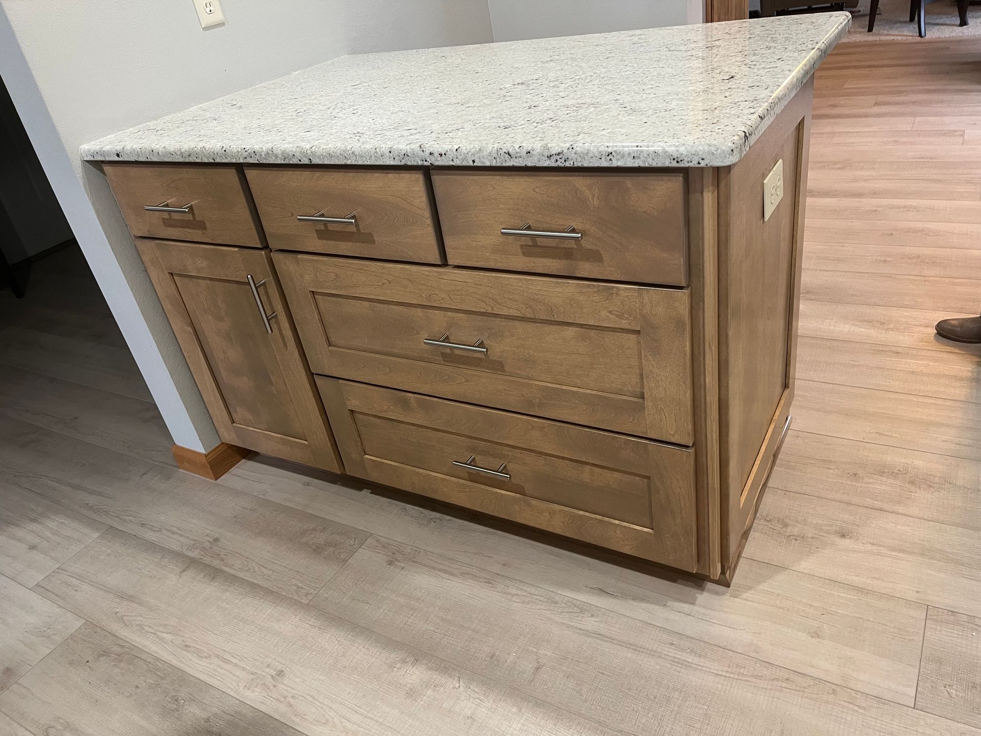 A kitchen island with drawers and a granite counter top.