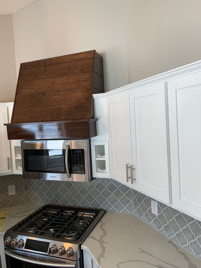 A kitchen with a stove , microwave , and wooden hood.