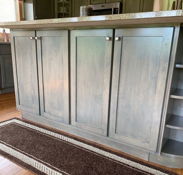 A kitchen with gray cabinets and a brown rug
