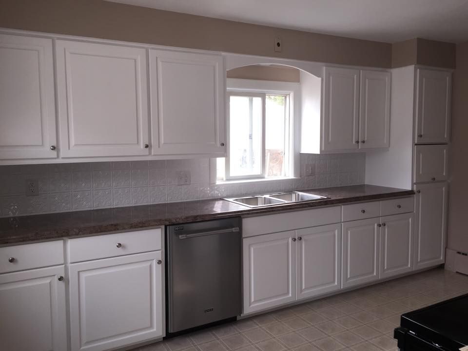 A kitchen with white cabinets and a stainless steel dishwasher