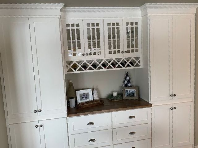 A kitchen with white cabinets , drawers , and a wine rack.