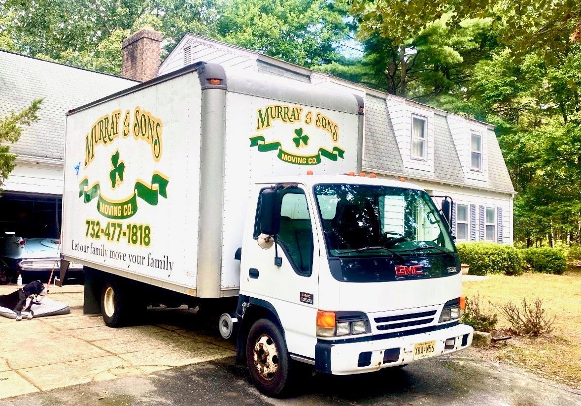 White delivery truck parked beside a building, with green-and-yellow branding on the box sides.