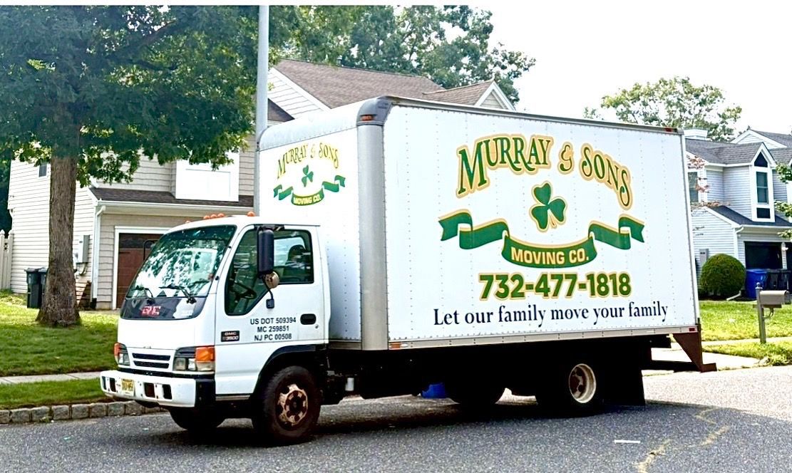 White delivery truck with “Murray’s” logo parked by a house in a leafy driveway