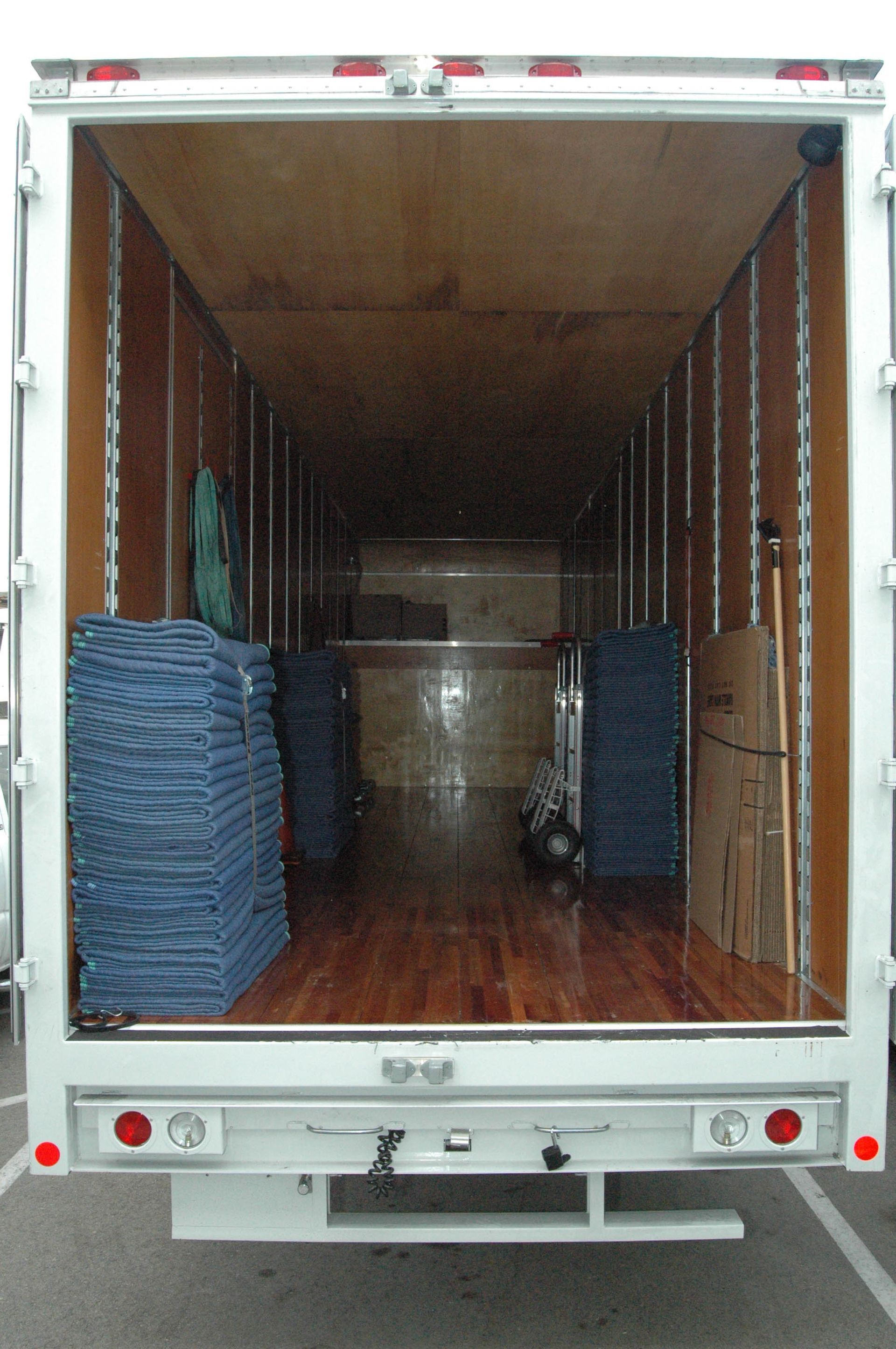Open box truck interior with stacked blue pallets and a wooden crate inside