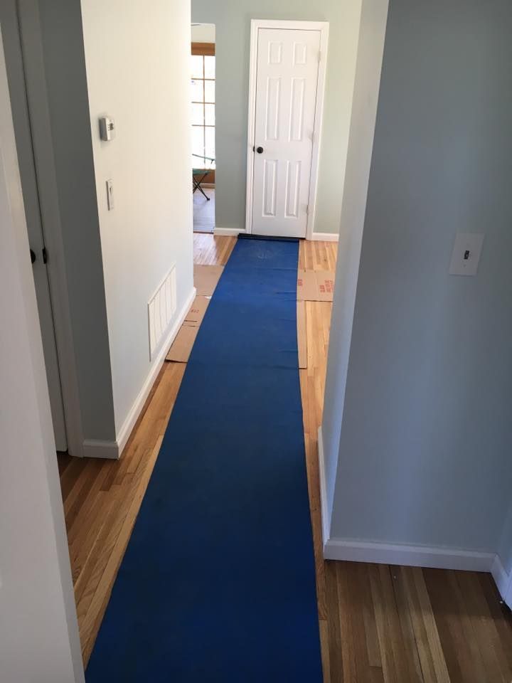 Narrow blue runner laid down in a hallway with wood floors and white doors.