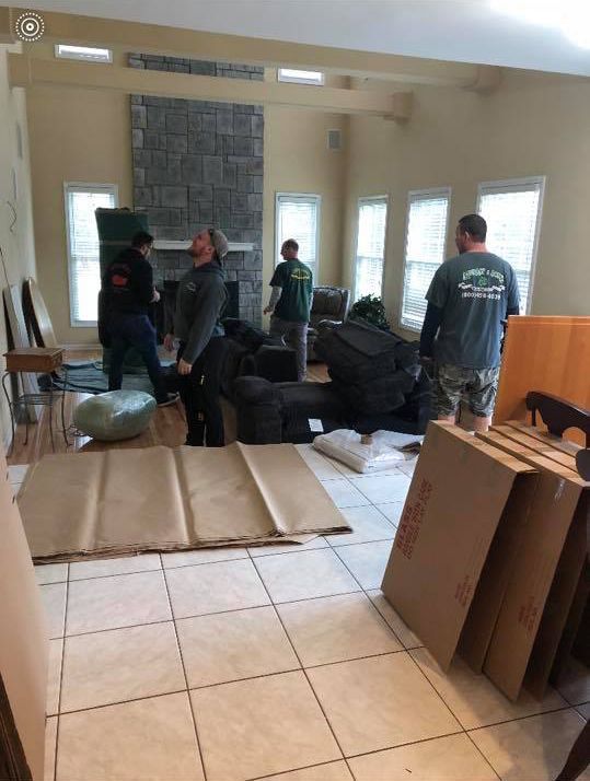 People moving furniture in a bright room with tiled floor and windows