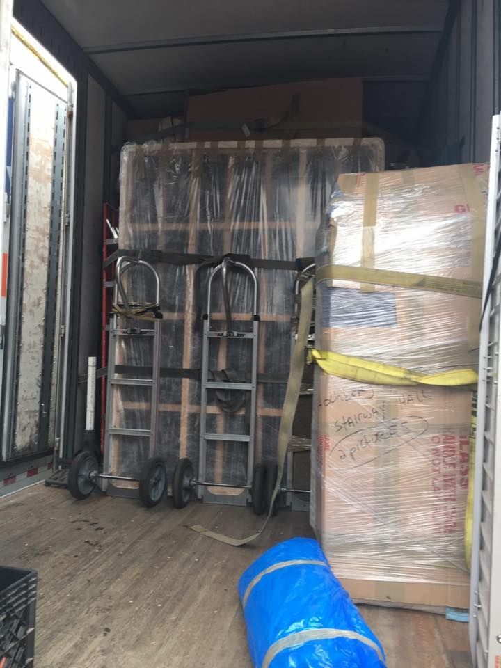 Loaded moving truck with stacked wrapped furniture and hand trucks inside