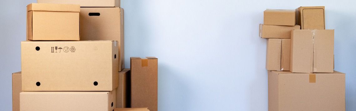 Stacks of cardboard moving boxes arranged against a light blue wall.