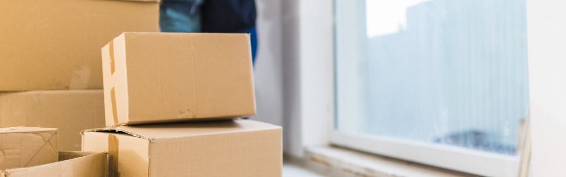 Stacked cardboard boxes beside a window in a bright room