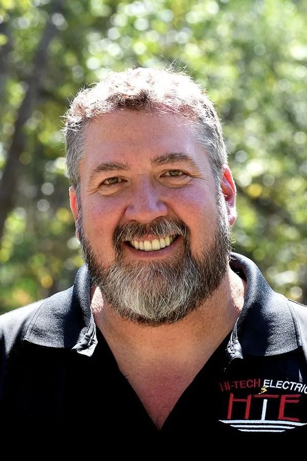 Smiling man with a beard wearing a black polo shirt with the company logo 