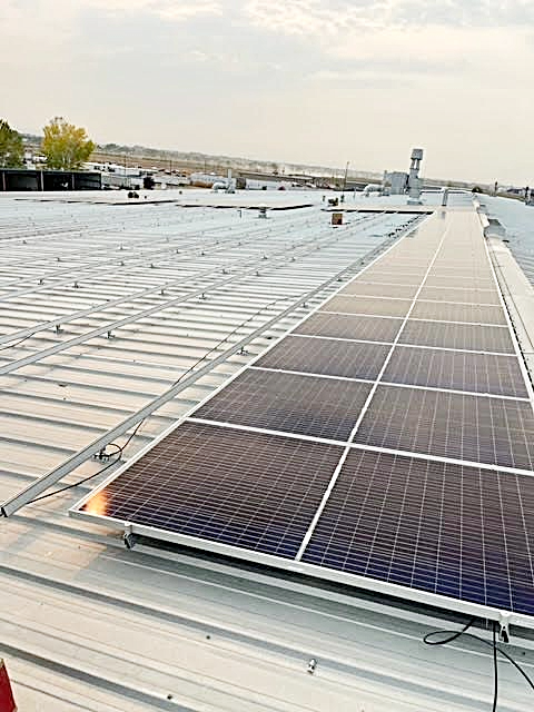 Solar panels installed on a metal rooftop on a cloudy day.