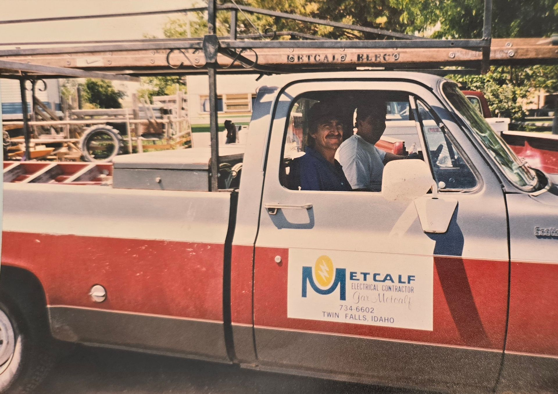Two people in a red and white pickup truck with 