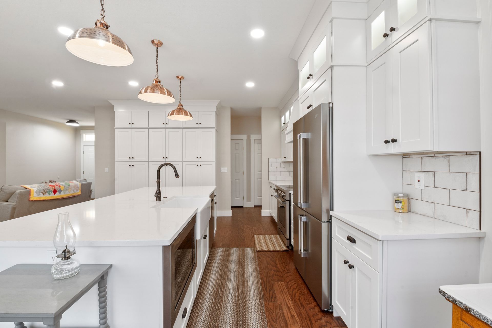 Bright, modern kitchen with white cabinets, stainless steel appliances, and a large island with copper pendant lights.