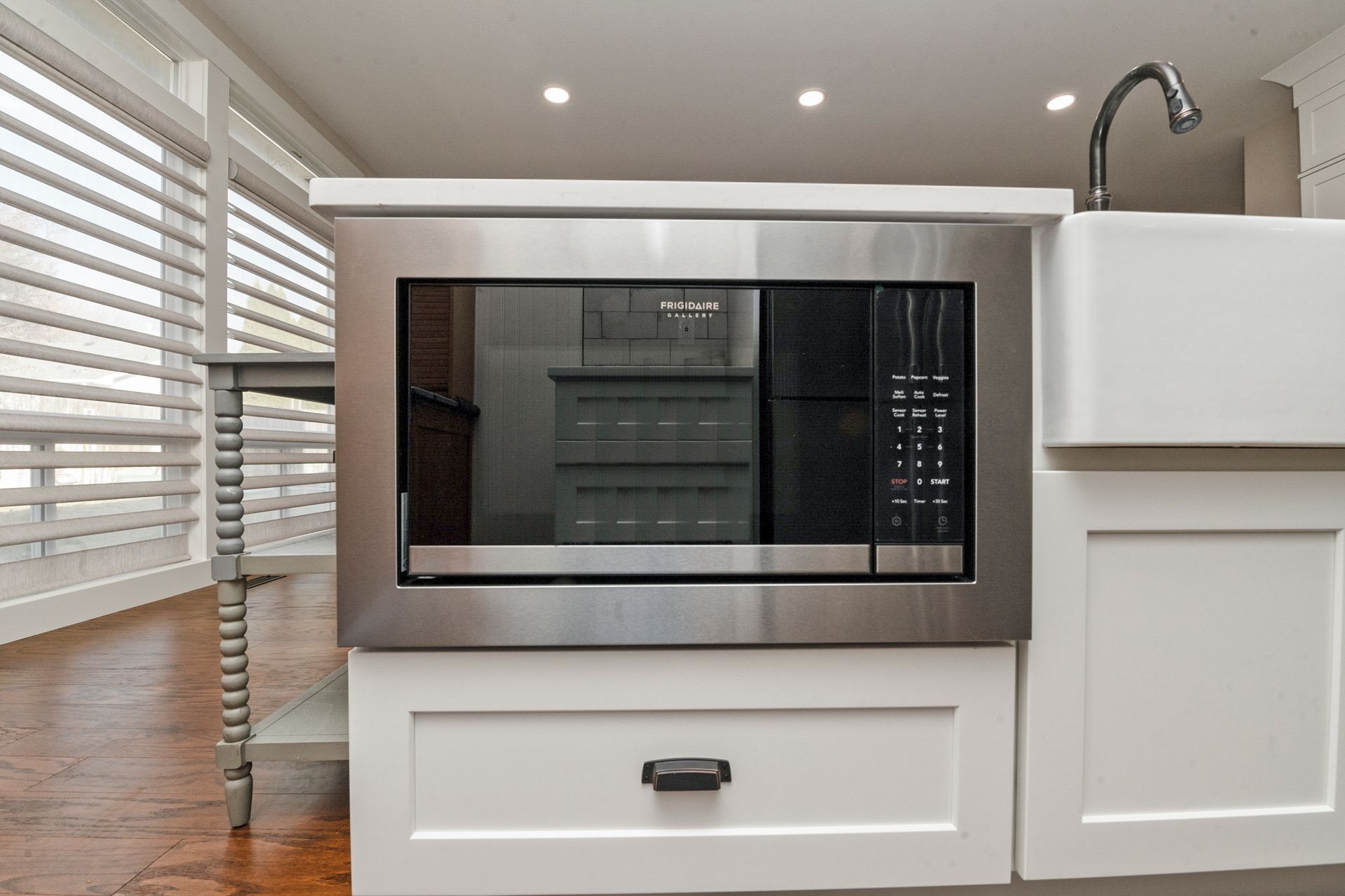 Built-in stainless steel microwave over a white cabinet. A sink is to the right.