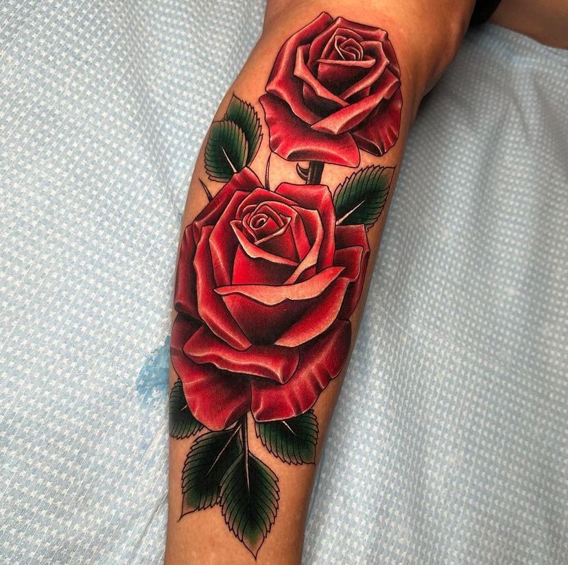 a tattoo of two red roses on a person's leg