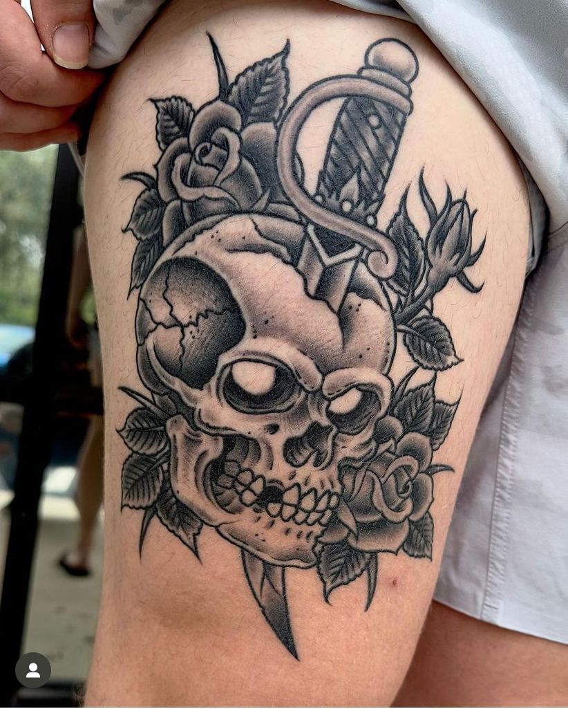 a black and white tattoo of a skull with roses and a dagger