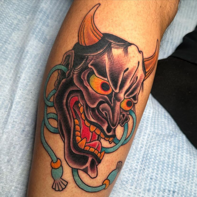a tattoo of a devil with horns on a leg