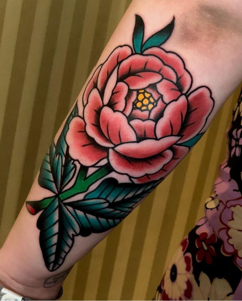 a woman has a tattoo of a pink flower on her arm
