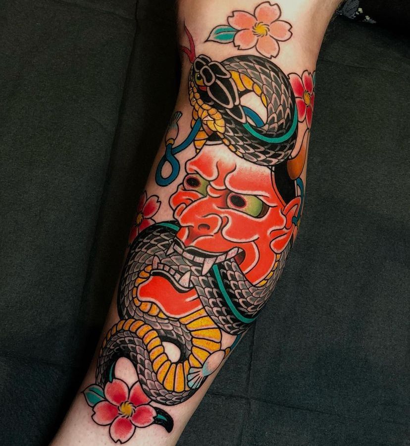 a person has a tattoo of a snake and flowers on their arm