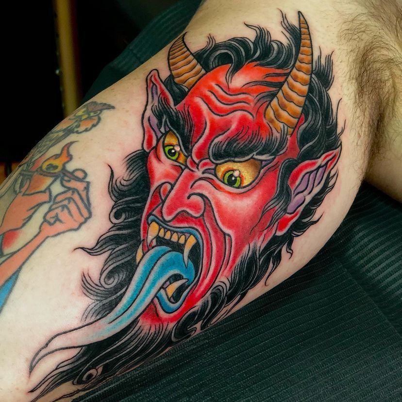 a man has a tattoo of a devil with horns sticking out his tongue