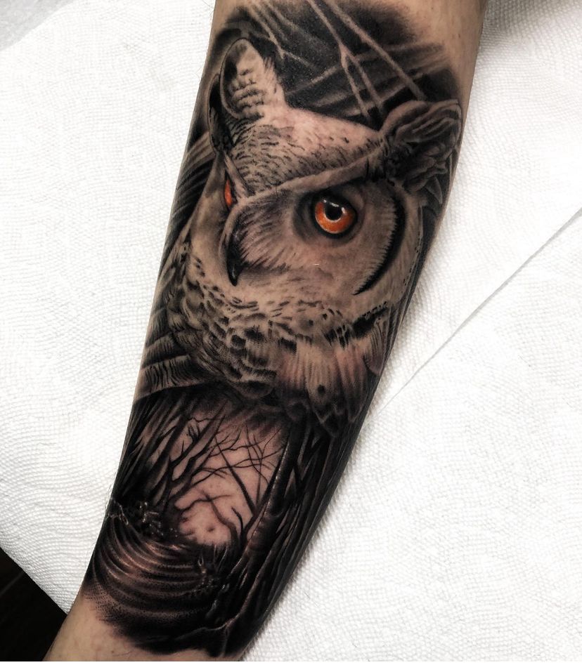 a person has a tattoo of an owl on their forearm