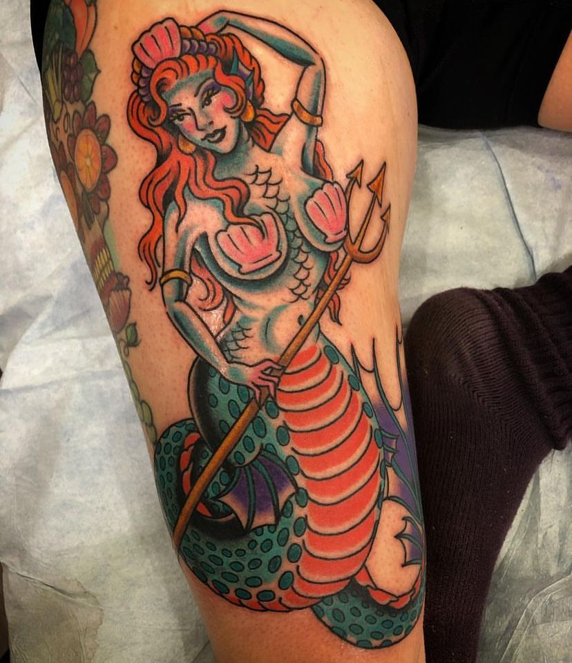 a tattoo of a mermaid with a trident on her arm
