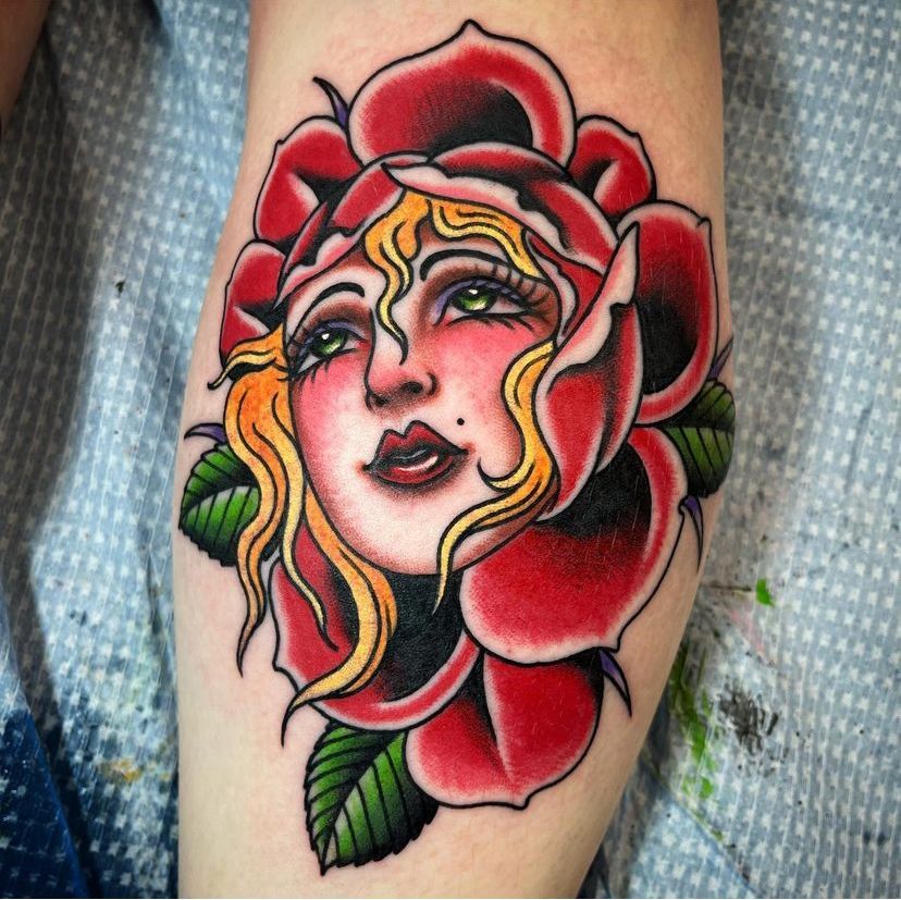 a tattoo of a woman's face with a red rose