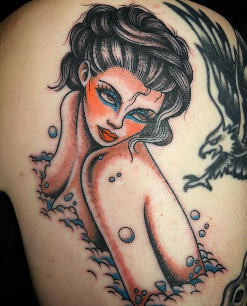 a woman has a tattoo of a mermaid on her back