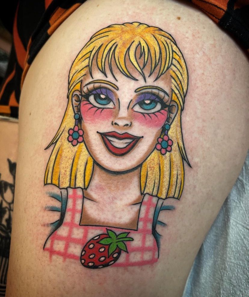 a tattoo of a barbie doll with a strawberry on her chest