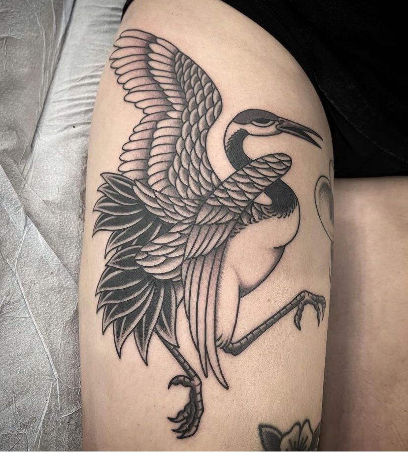 a black and white tattoo of a bird on a person's thigh