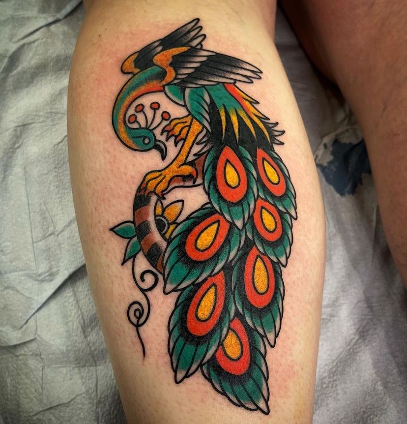a colorful peacock tattoo on a person's leg