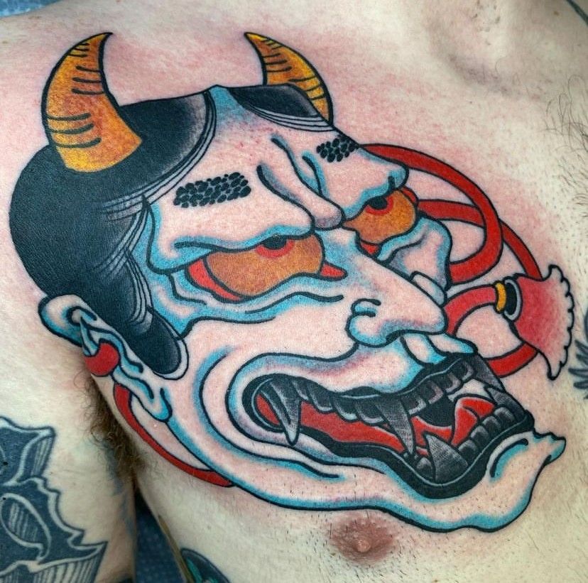 a man has a tattoo of a devil with horns on his chest