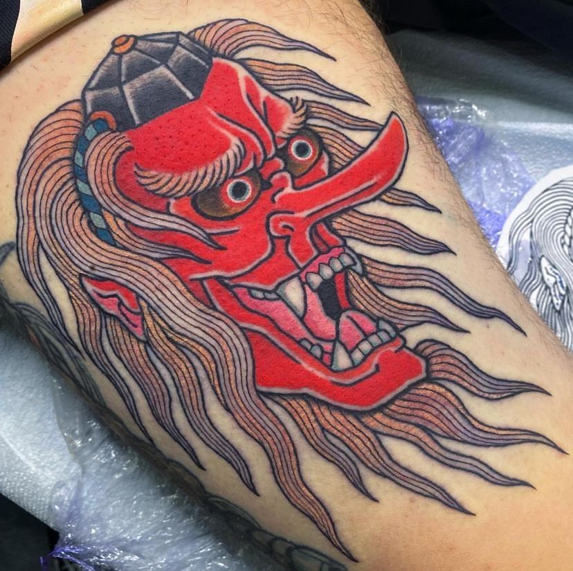 a person has a tattoo of a red demon on their leg