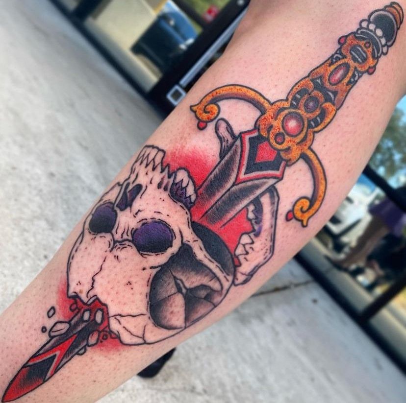 a person has a tattoo of a skull and a dagger on their arm