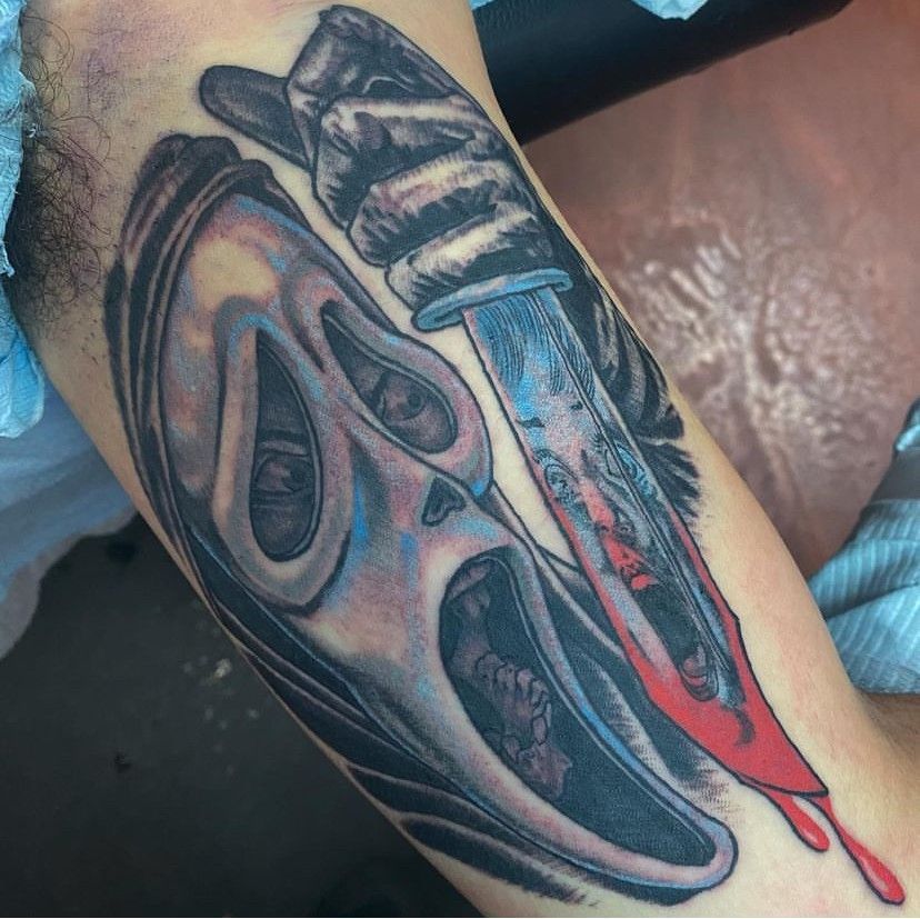 a tattoo of a skull and a bloody knife