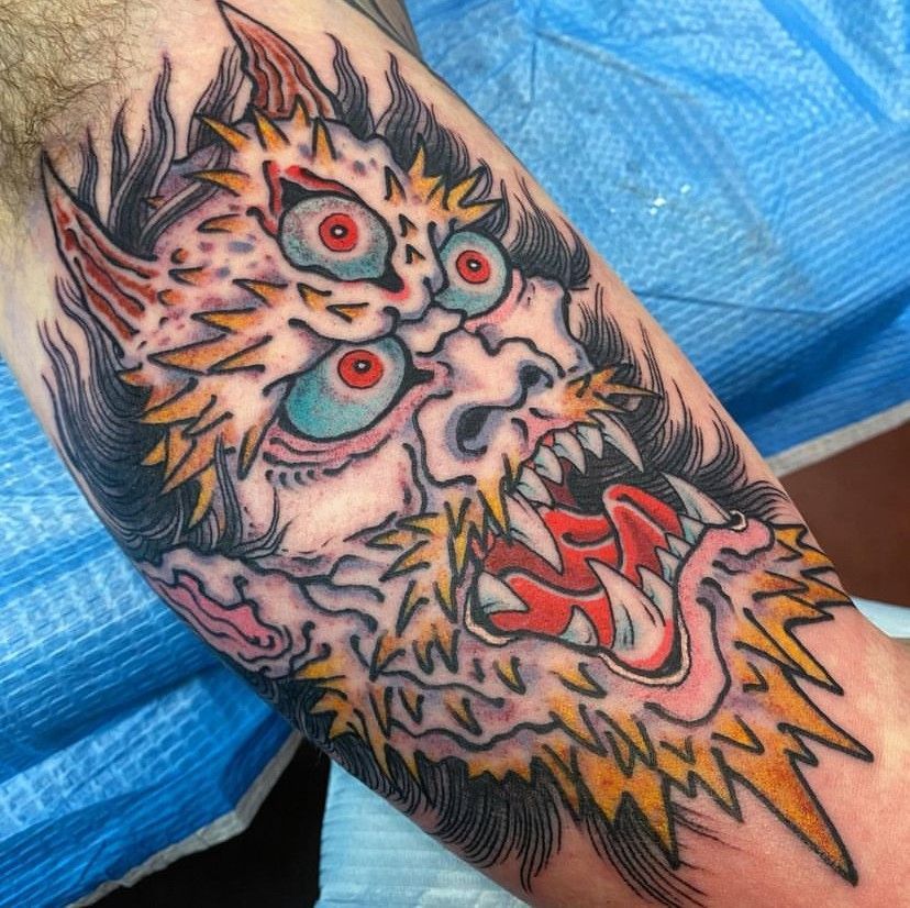 a man has a tattoo of a monster on his arm
